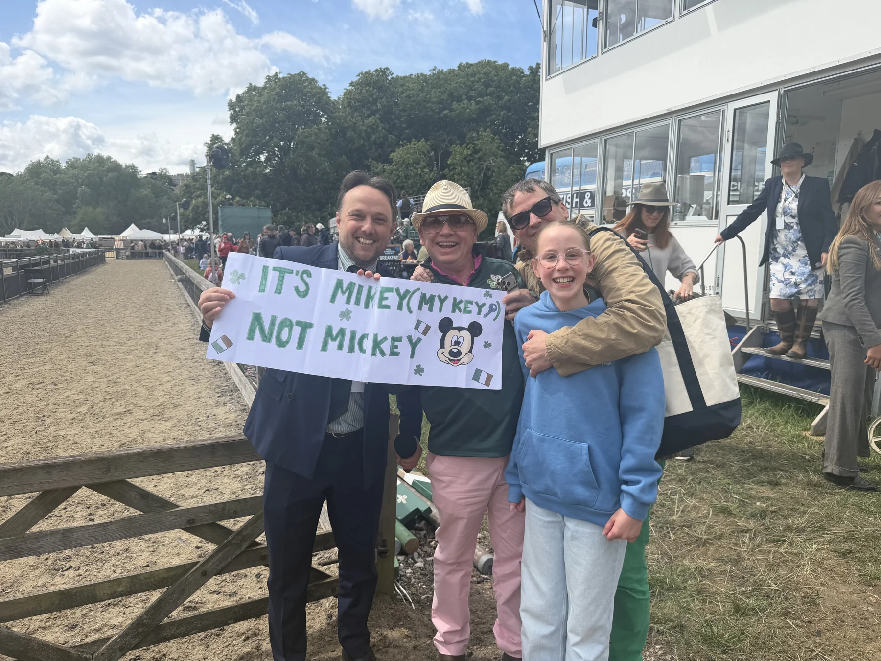 Family at Royal Windsor holding a hand-painted sign: 'It's Mikey (My-key), not Mickey.'